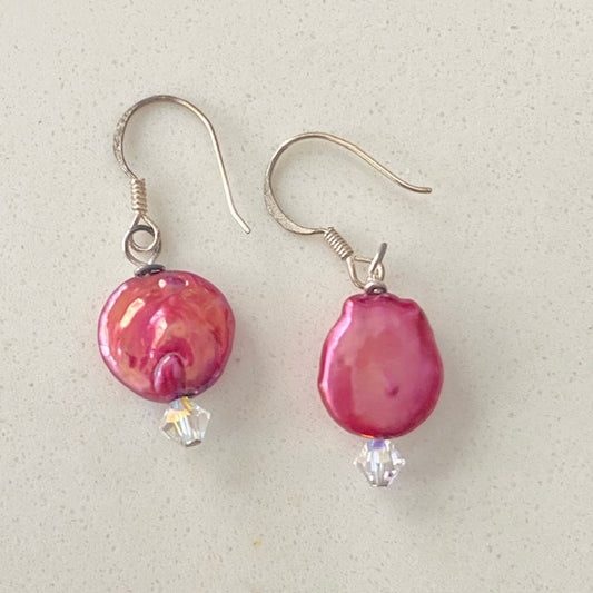 Overhead view of the Sterling silver  fishhook earrings featuring the dyed bright cranberry-coloured coin pearls with Austrian crystal accents