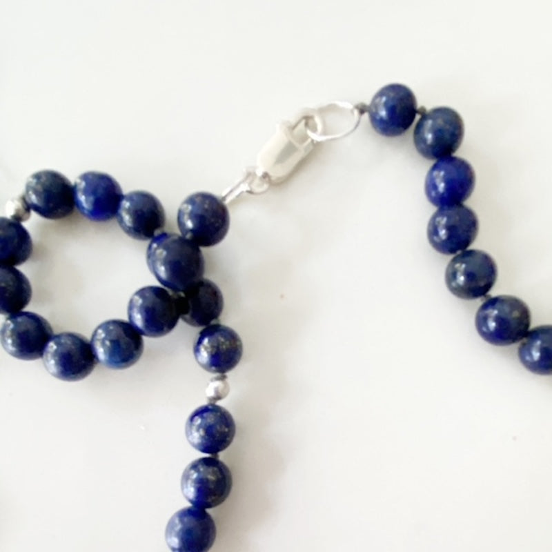 Closeup of the hand-knotted round deep blue Lapis Lazuli beads and sterling silver lobster clasp in the Kinetic necklace