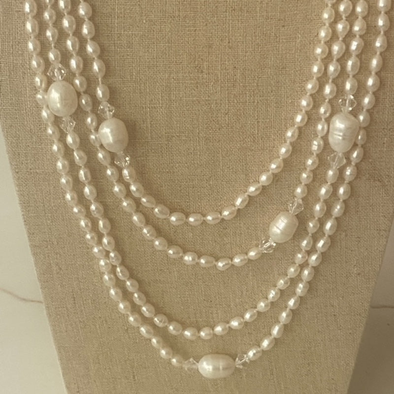 Closeup of the super long 96-inch knotted pearl necklace show draped on a linen jewelry stand
