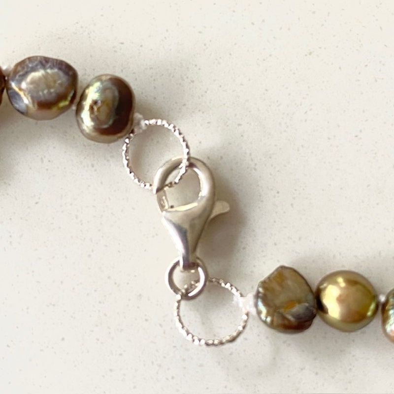 Closeup of sterling silver rounded lobster clasp joining both sides of the hand-knotted pearl bronze choker strand