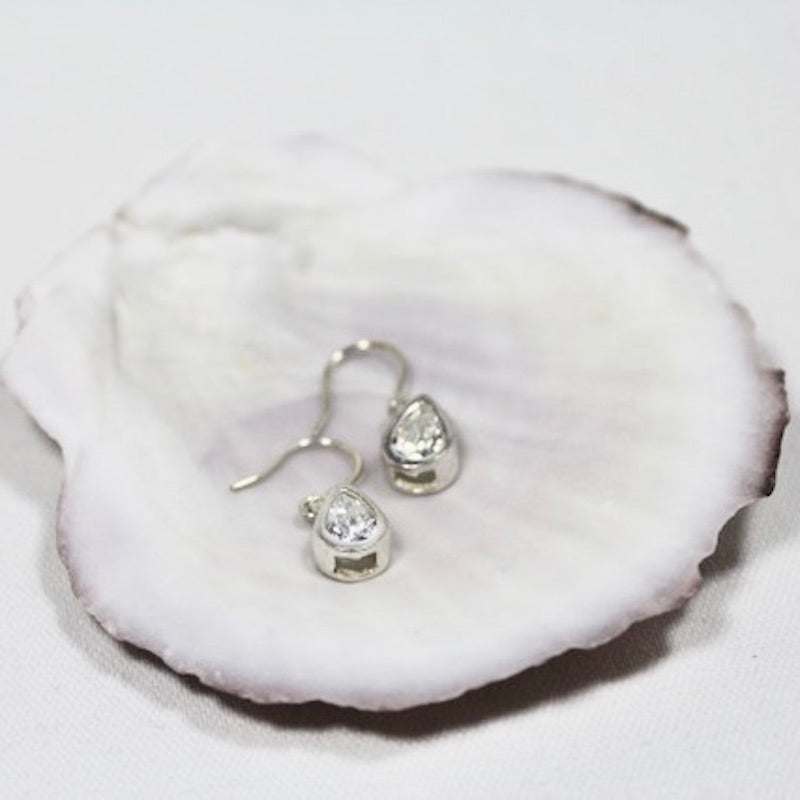 Pair of cubic zirconia sterling silver matching teardrop earrings shown displayed on a shell