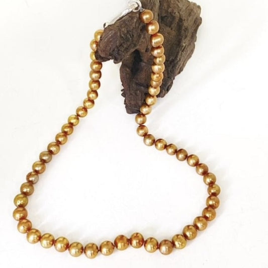 Honour gold freshwater pearl hand-knotted necklace 20-inch with sterling clasp shown on driftwood prop