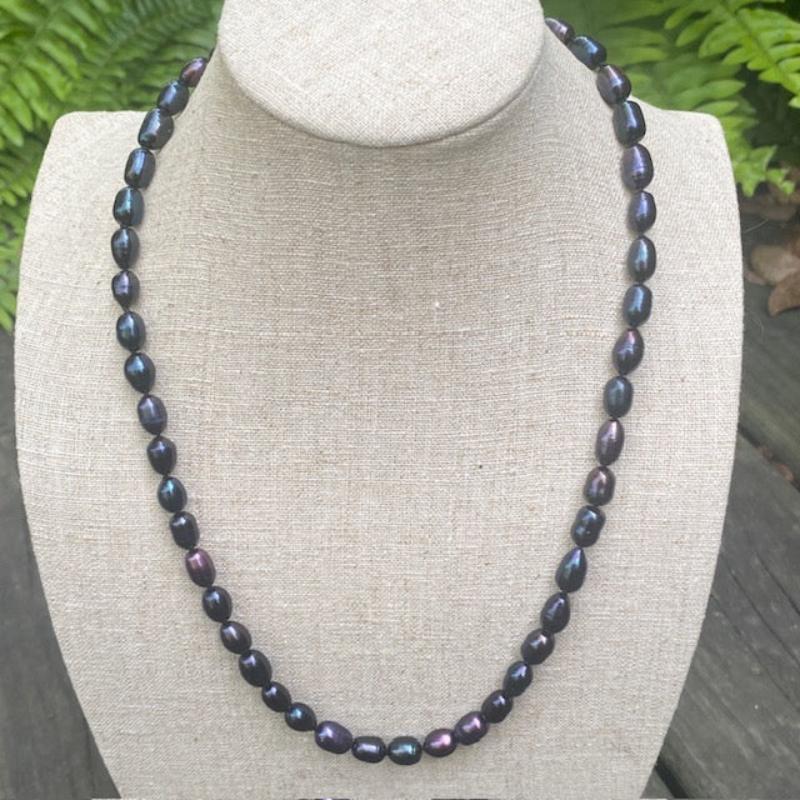 Necklace shown on linen jewelry stand outside 