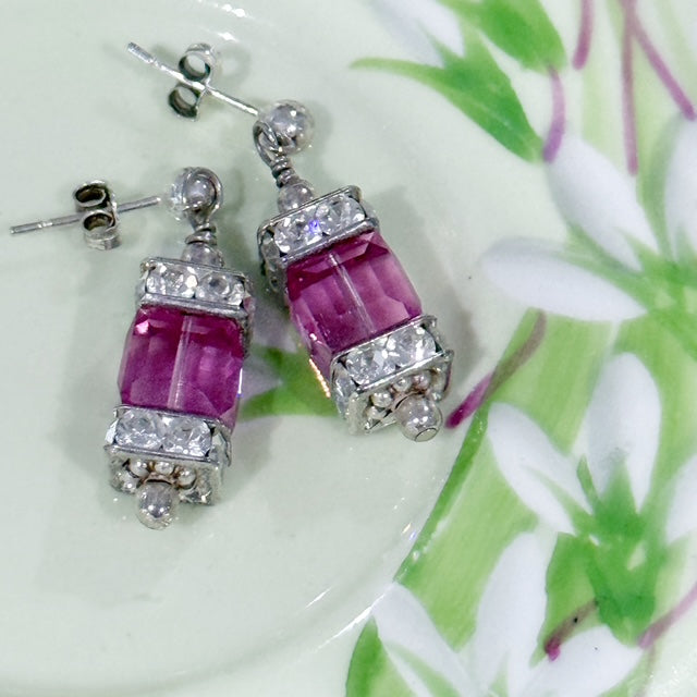 Pink gemstone earrings with silver accents on a floral background