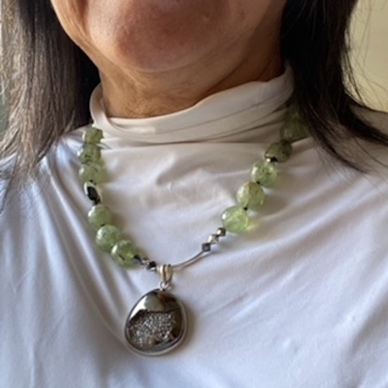 Model wearing the 18-inch knotted green Prehnite necklace with Black Drusy pendant on her white top
