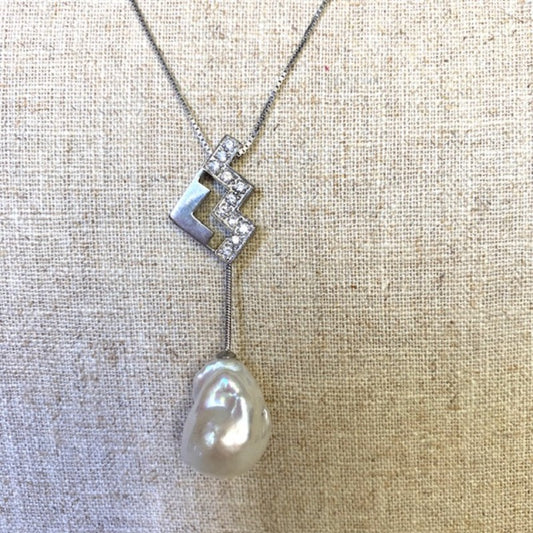 Closeup of White Baroque Pearl with Art deco inspired silver and crystal studded accent  on a sterling silver chain shown on linen bust