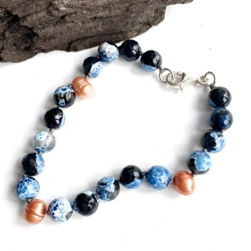 Blue Black Swirled Agate Hand-knotted Bracelet with Orange Pearl Accents Sterling Silver Clasp shown with driftwood display
