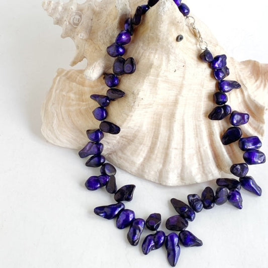 Blue-purple dyed blister pearls knotted into 17 1/2-inch necklace shown draped on conch shell