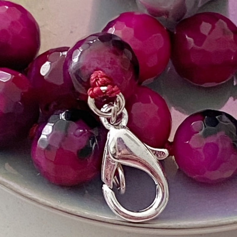 Closeup dyed magenta agate beads and silver-plated lobster clasp