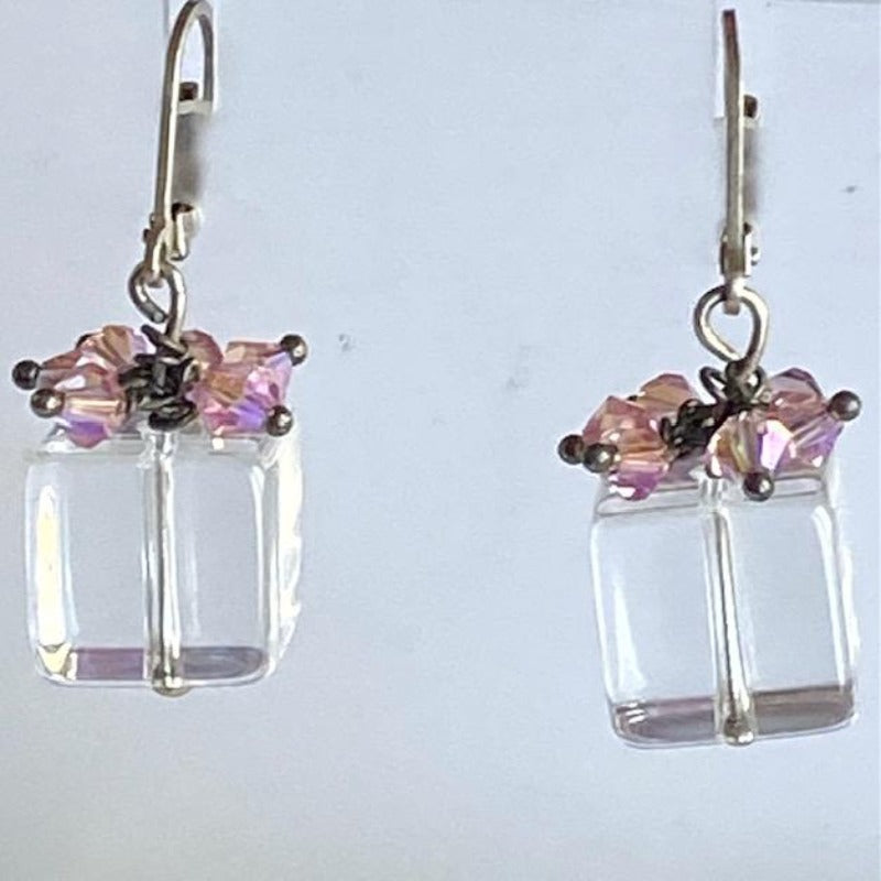 Clear cube earrings with sparkling pink crystals designed to look like mini presents shown hanging on earring display 