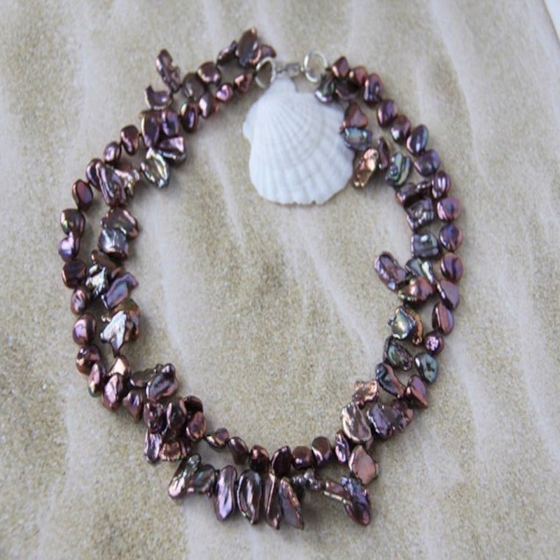 17 Inch Double Strand Hand-knotted Maroon Keshi Pearl Necklace shown on seashell and sand background