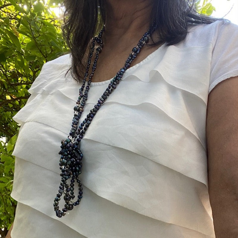 Long hand-knotted 47-inch inky black pearl and crystal necklace shown loosely front-knotted worn by model