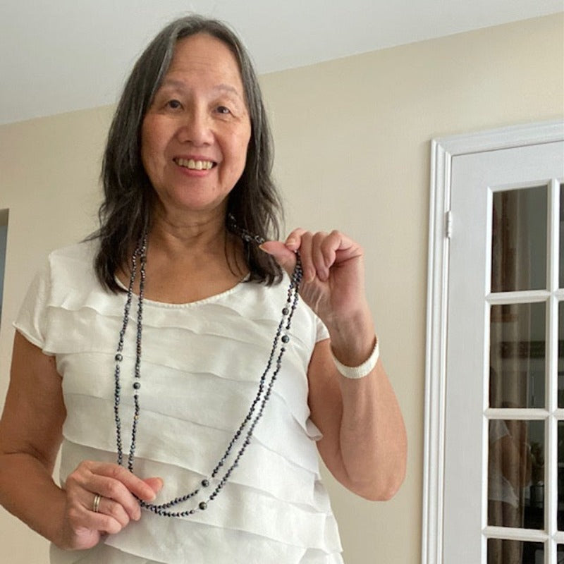 Long hand-knotted 47-inch inky black pearl and crystal necklace shown long with double strands separated on model