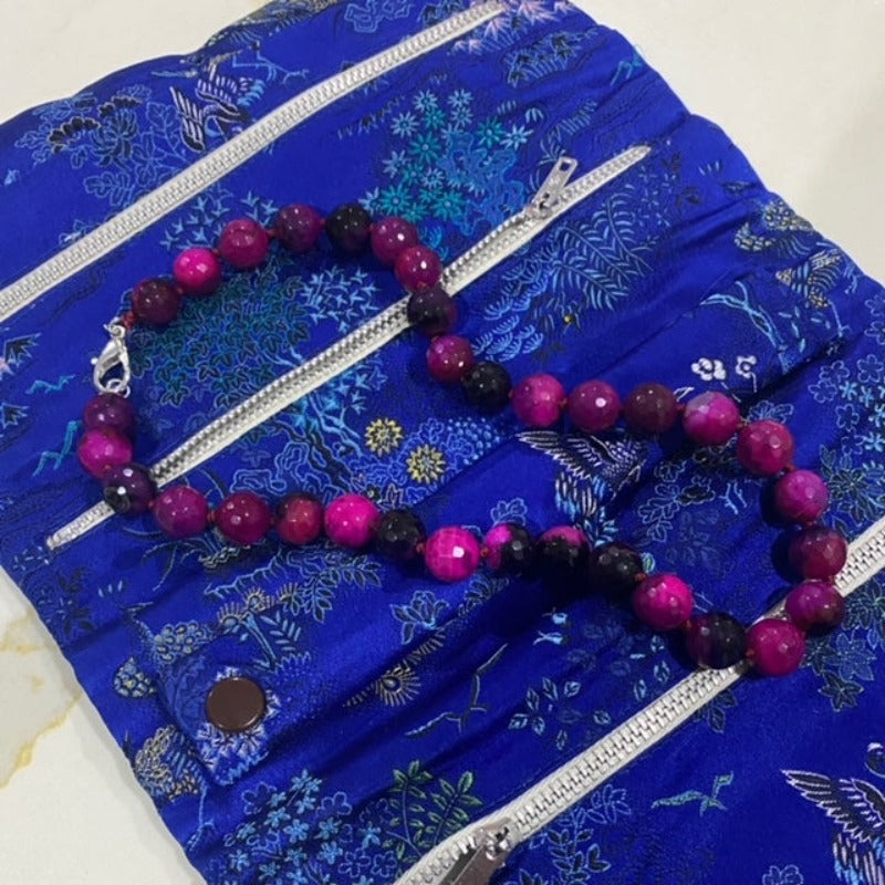 Dyed magenta agate 18-inch knotted necklace shown on jewelry brocade prop bag