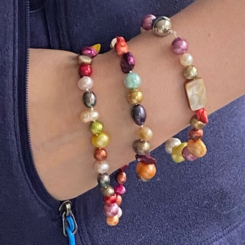 Model wearing three knotted multi-coloured pearl bracelets with the centre one being the 7-inch bracelet in this listing