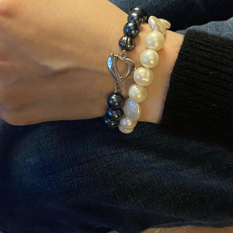 White coin and round pearl knotted bracelet shown styled along with knotted navy pearl bracelet with heart bar toggle clasp
