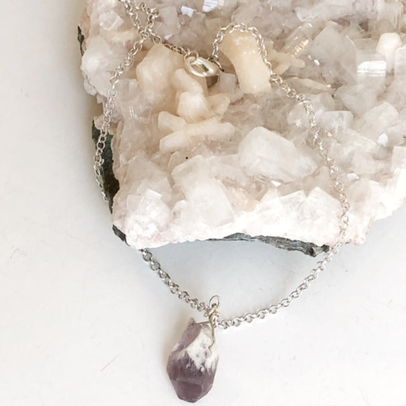 Amethyst organic raw chunky 1 inch pendant with silver-plated chain shown on crystal prop