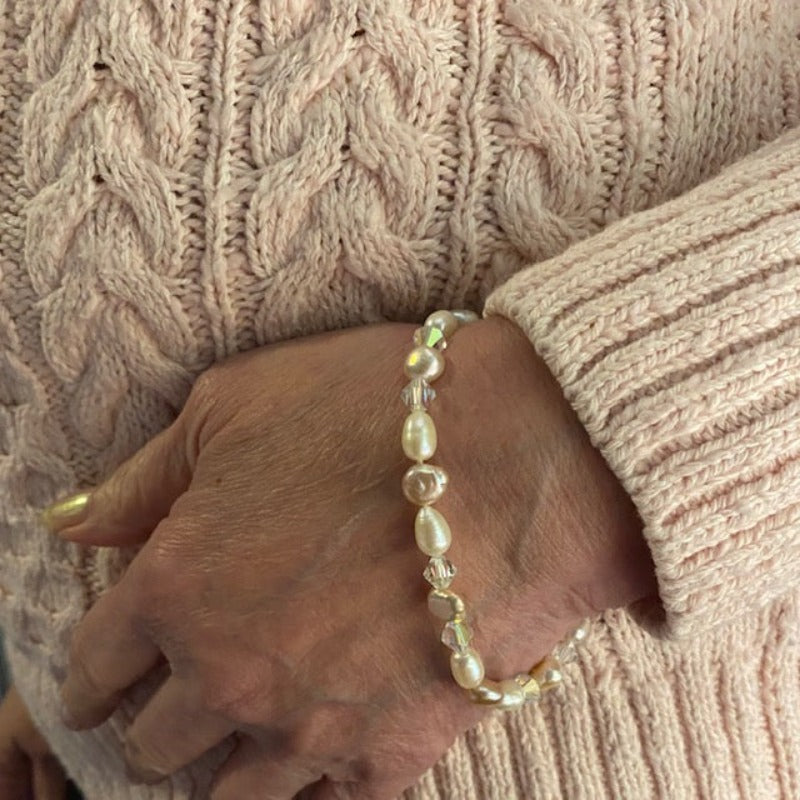 Pale pink and white freshwater pearl bracelet with sparkling crystals shown on model in pink sweater