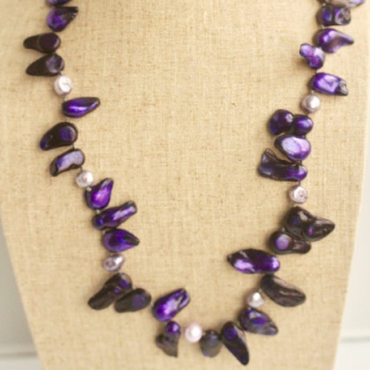 Partial View of knotted Purple Blister Pearl Necklace hanging on Linen Bust