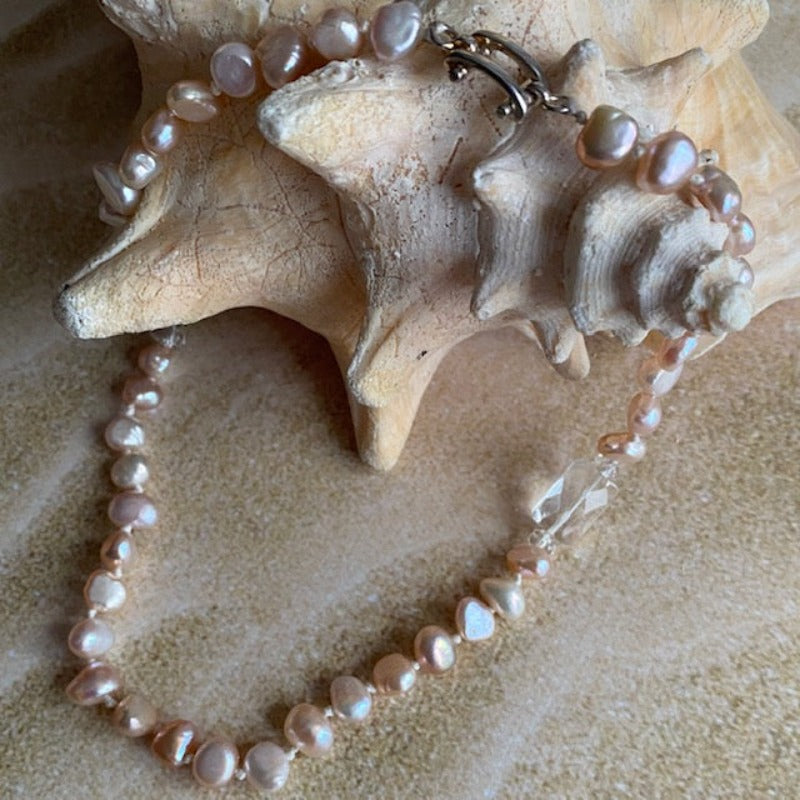 Pink pearl and white rectangular facetted crystal knotted necklace shown on shell prop