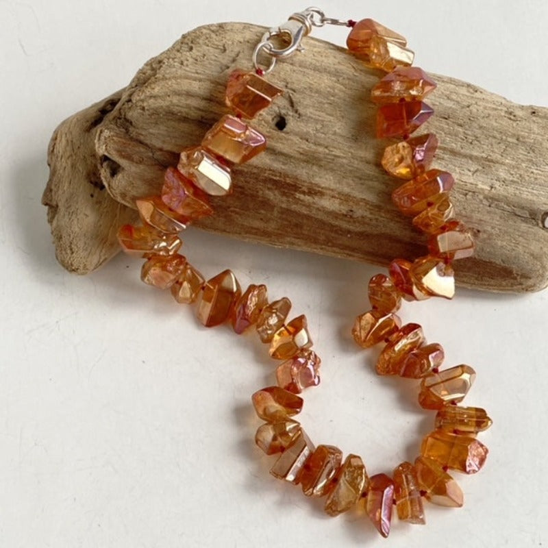 Shiny golden-orange electroplated quartz rounded spike nugget knotted statement  necklace shown on driftwood prop