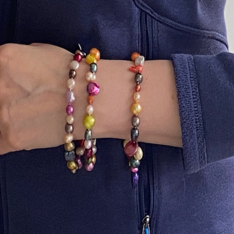 Model wearing three multi-coloured knotted bestseller bracelets for styling purposes. 